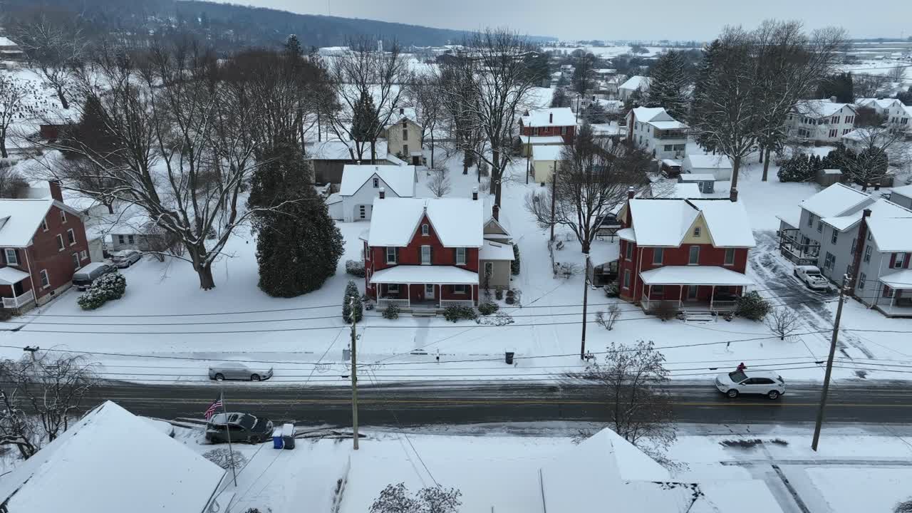 Snow blankets a quiet residential neighborhood, featuring classic homes captured by a drone in the USA