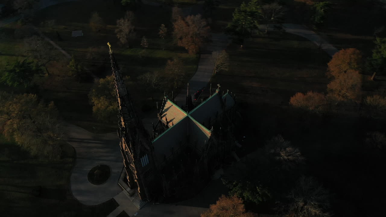 una toma aérea sobre una catedral con un campanario alto, tomada en las sombras al amanecer