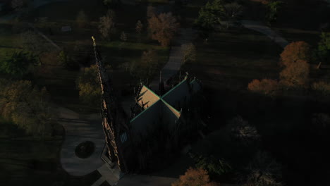 an aerial shot over a cathedral with a tall steeple, taken in the shadows at sunrise