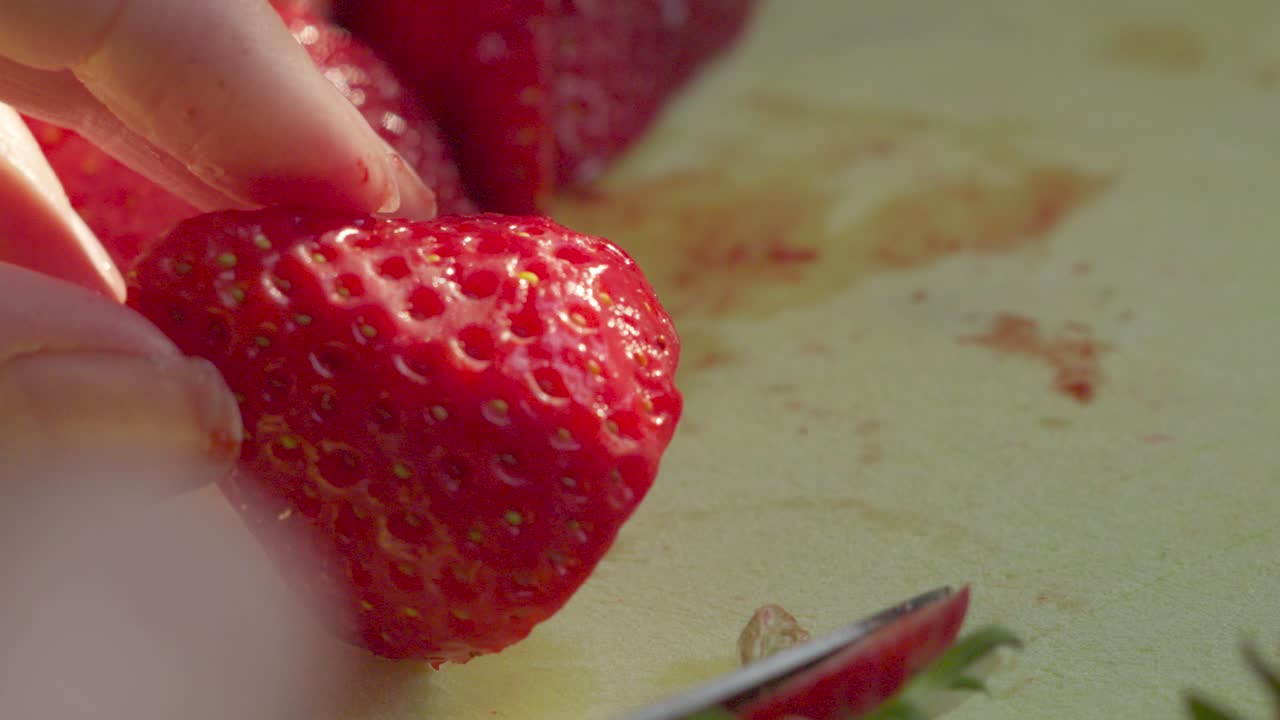 저녁 빛으로 절단판에서 느린 동작으로 딸기 부분을 잘라내는 것
