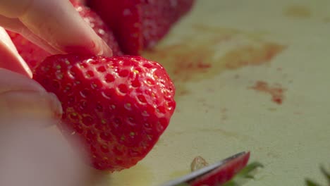 abschneiden von erdbeeren in langsamer bewegung auf einem schneidbrett mit abendsonnenlicht