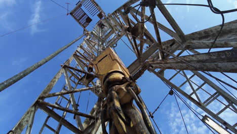drilling equipment hanging on the thick metal wires vibrating from work. low angle view on the derrick for oil production.