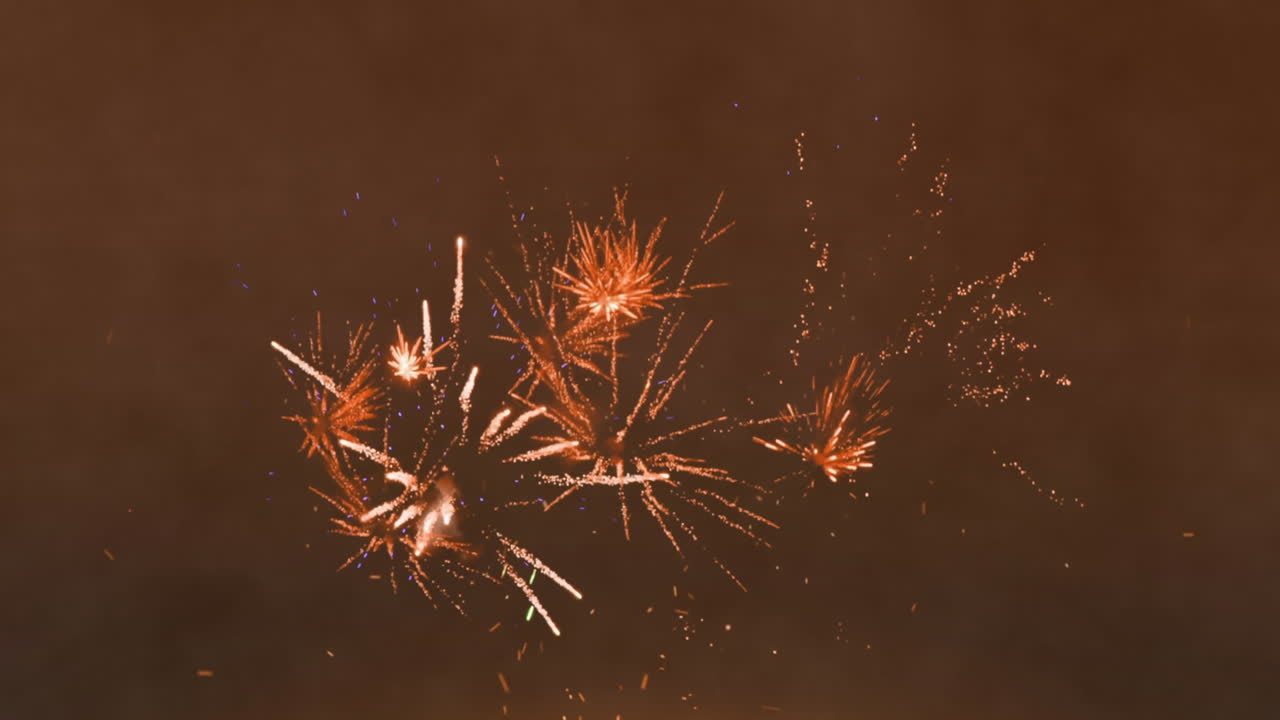 animación de chispas de luz sobre fuegos artificiales que explotan contra un fondo marrón con espacio de copia