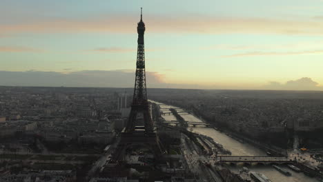Aerial-shot-of-seine-river-calmly-flowing-through-metropolis-around-Eiffel-Tower.-Large-city-at-dusk,-twilight-sky-in-background.-Paris,-France