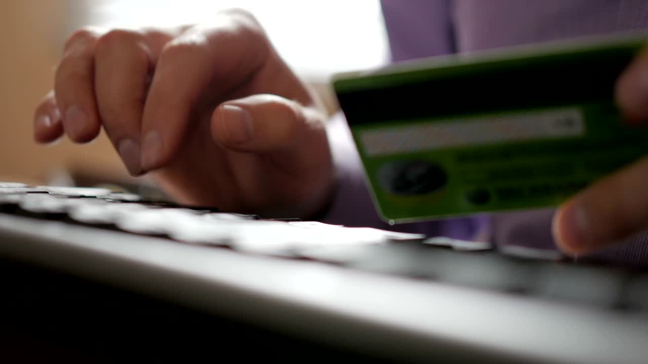 pagar con una tarjeta de crédito en línea, comprar. manos masculinas con tarjeta de crédito durante las compras a través de internet. teclado de computadora. primer plano. hombre de negocios hizo un pago electrónico.