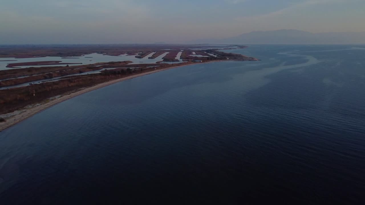 воздушный подъем над пляжем и лагунами, используемыми для разведения рыбы в греции, в сумерках