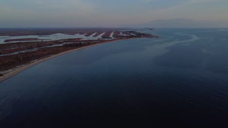 aerial ascent over beach and lagoons used for fish-farming in greece at dusk