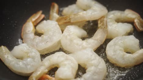 unrecognizable cook frying prawns in pan with hot oil