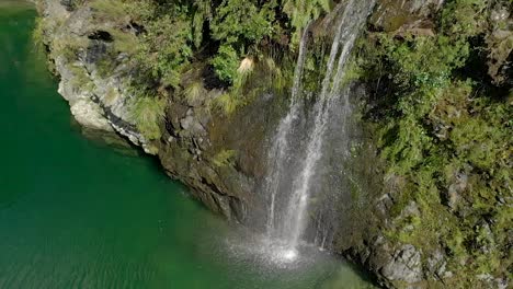 Beautiful-waterfall-on-beautiful-pristine-blue-clear-Pelorus-river,-New-Zealand-with-rocks-and-native-lush-forrest-in-background---Aerial-Drone