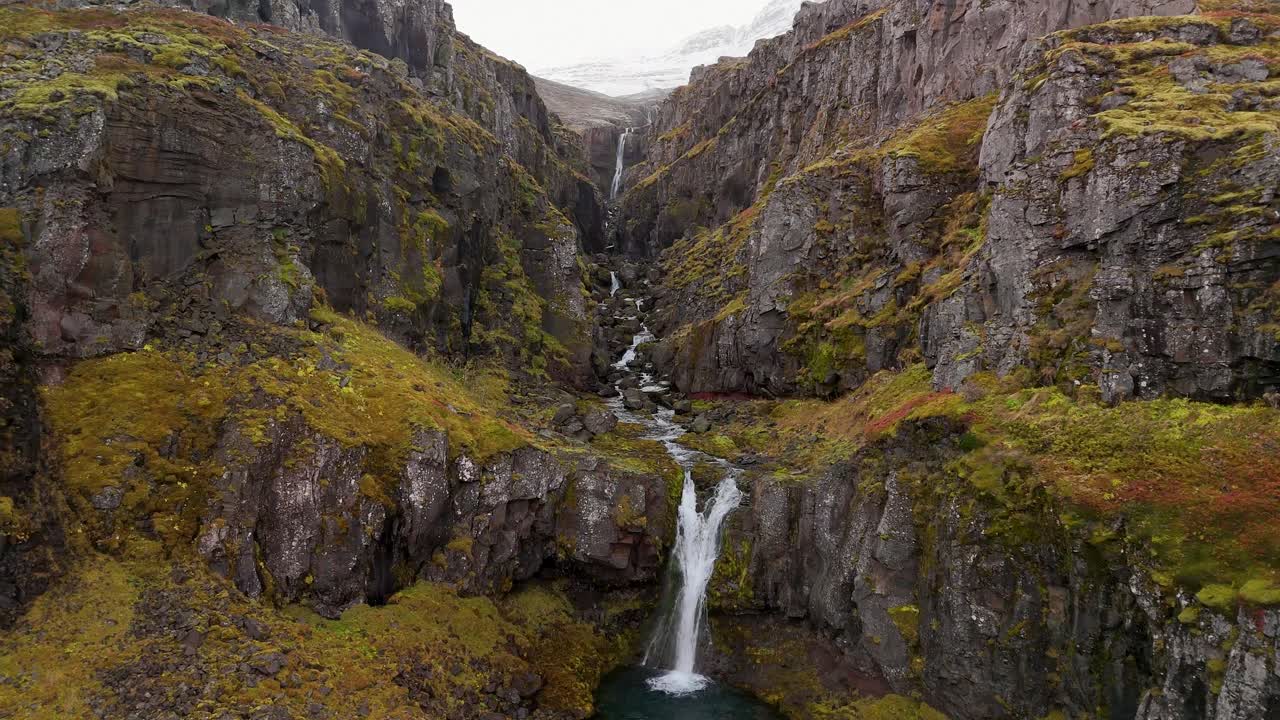 Aerial View of a Stunning Waterfall cascading down mossy cliffs in Iceland