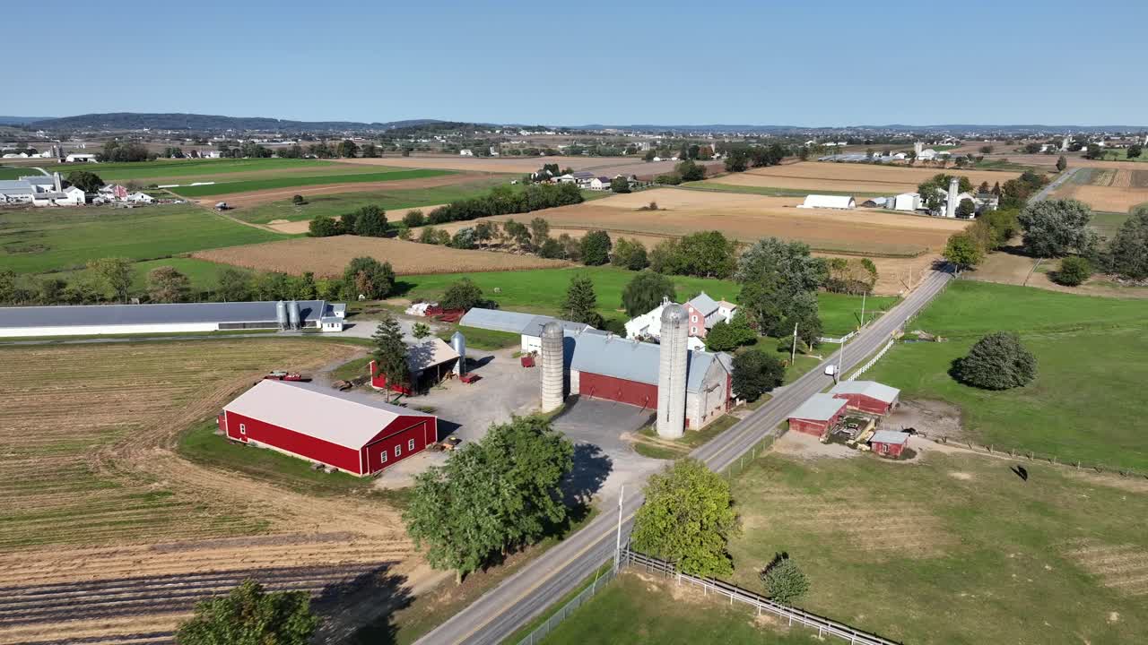 Aerial flyover american countryside with main street along farm houses and silos. Sunny autumn day in american city suburb. Colorful landscape with blue sky and sunlight. Wide shot.