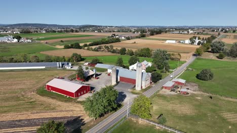 aerial flyover american countryside with main street along farm houses and silos. sunny autumn day in american city suburb. colorful landscape with blue sky and sunlight. wide shot.