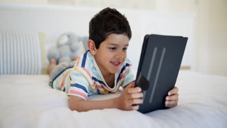 niño jugando en la tableta en el dormitorio