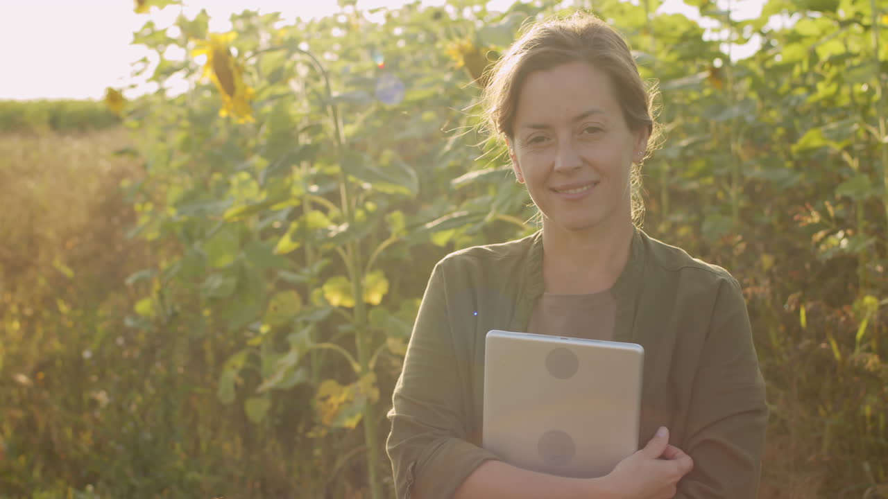 Donna con tablet in un campo di girasoli