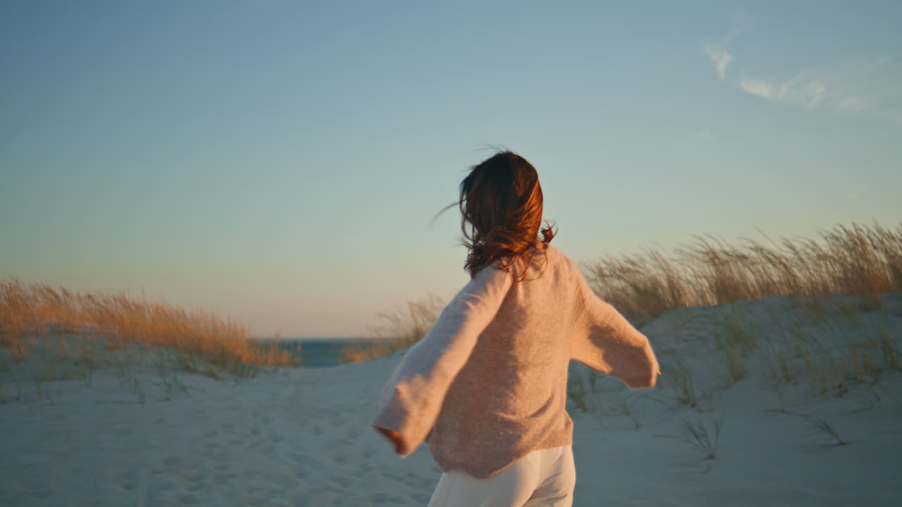 Romantic girl walking evening desert enjoying windy weather. Smiling woman