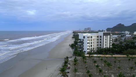 Stunning-aerial-of-an-exotic-beach-on-an-overcast-day-with-appartements-and-mountains