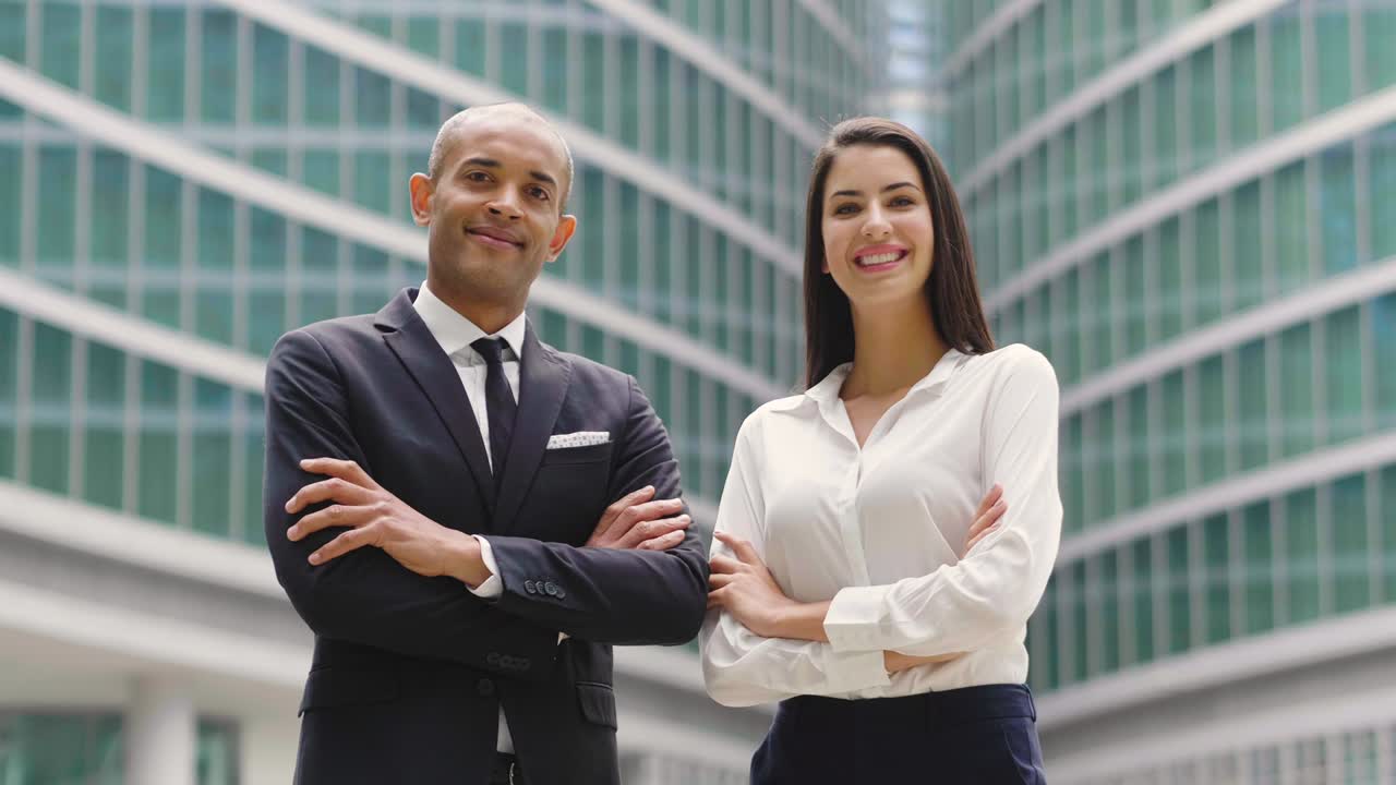 retrato de un hombre y una mujer de negocios de diferentes etnias, mirando a la cámara y sonriendo, cruzando los brazos.