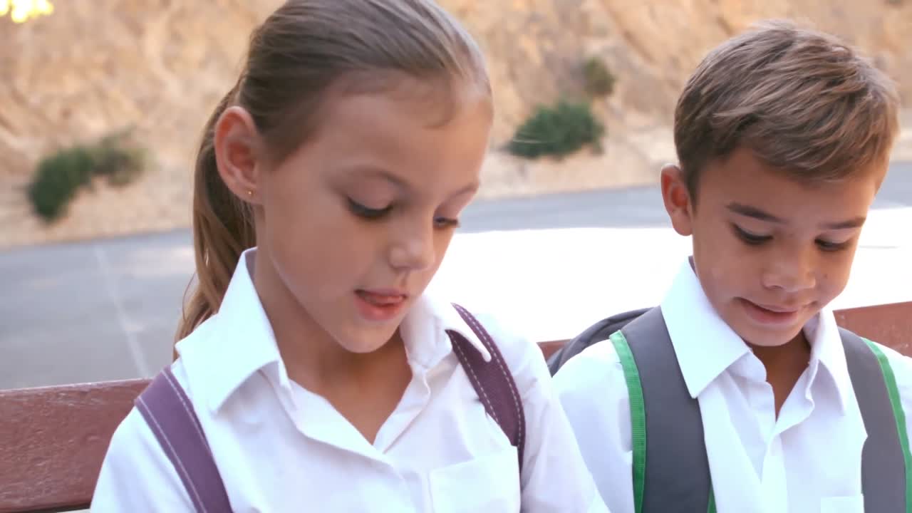 школьники сидят на скамейке.