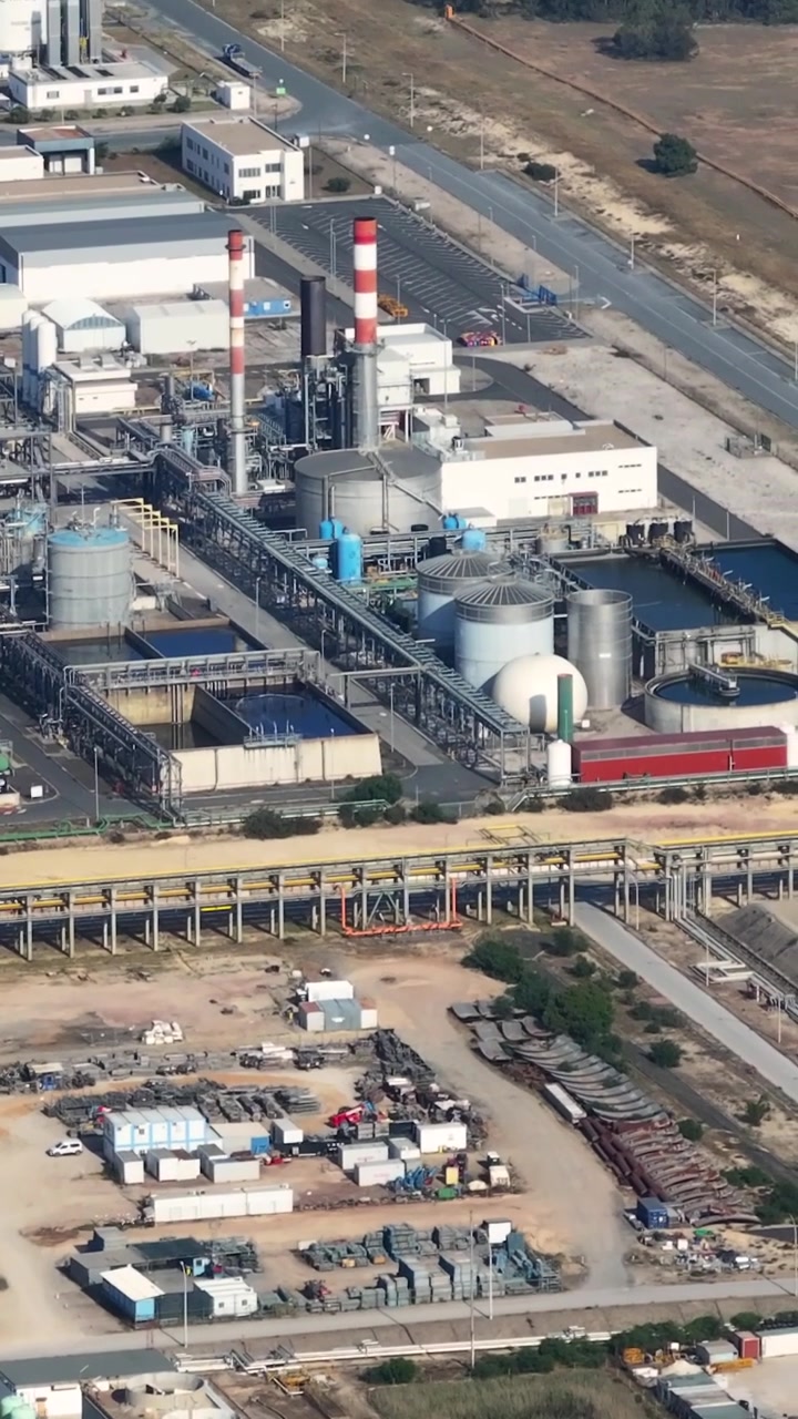 This aerial view shows an oil refinery complex with various processing facilities and energy infrastructure. The video captures the scale and layout of the petroleum production facility.