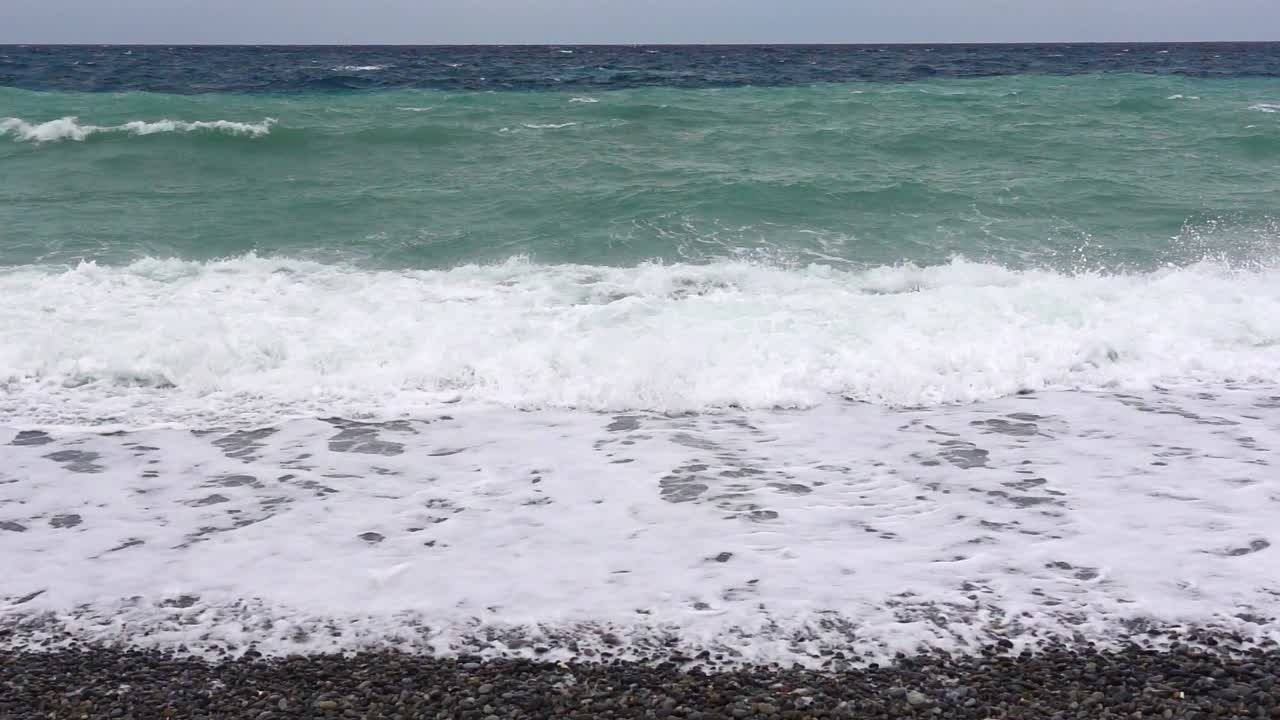 Stormy waves crash in slow motion on a pebble beach in Surigao City, creating a powerful scene