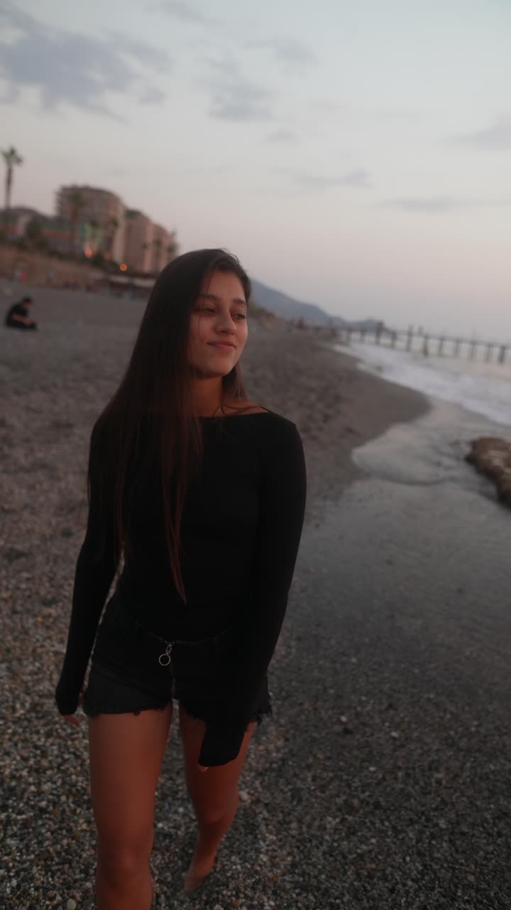 donna che cammina sulla spiaggia al tramonto