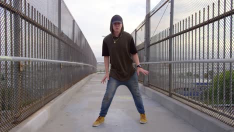 hombre de freestyle hip hop bailando a través del paso elevado de la autopista en la ciudad