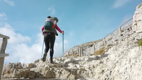 una mujer camina con una mochila de día y bastones de senderismo, conquistando las 3 cime lavaredo de veneto en los dolomitas de italia para una aventura al aire libre