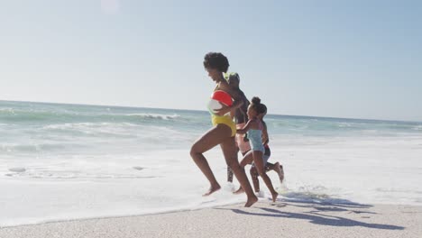 Smiling-african-american-family-with-inflatables-running-on-sunny-beach