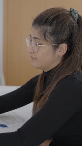 young woman studying at a desk with documents and office supplies