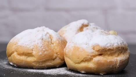 baked custard eclairs and sprinkled with powdered sugar and decorated with a mint leaf on a black board