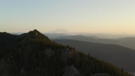 slow moving parallax effect with ridge in foreground and mountain range in background, aerial shot during dusk, golden hour