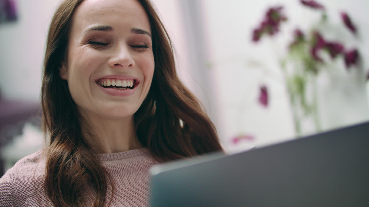 Happy woman laughing looking at laptop at home