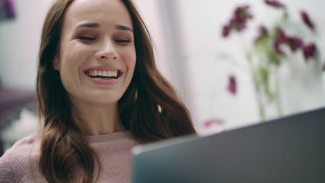 mujer feliz riendo mirando la computadora portátil en casa