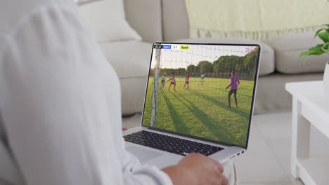 Video-Einer-Person,-Die-Auf-Der-Couch-Sitzt-Und-Sich-Ein-Fußballspiel-Auf-Dem-Laptop-Ansieht