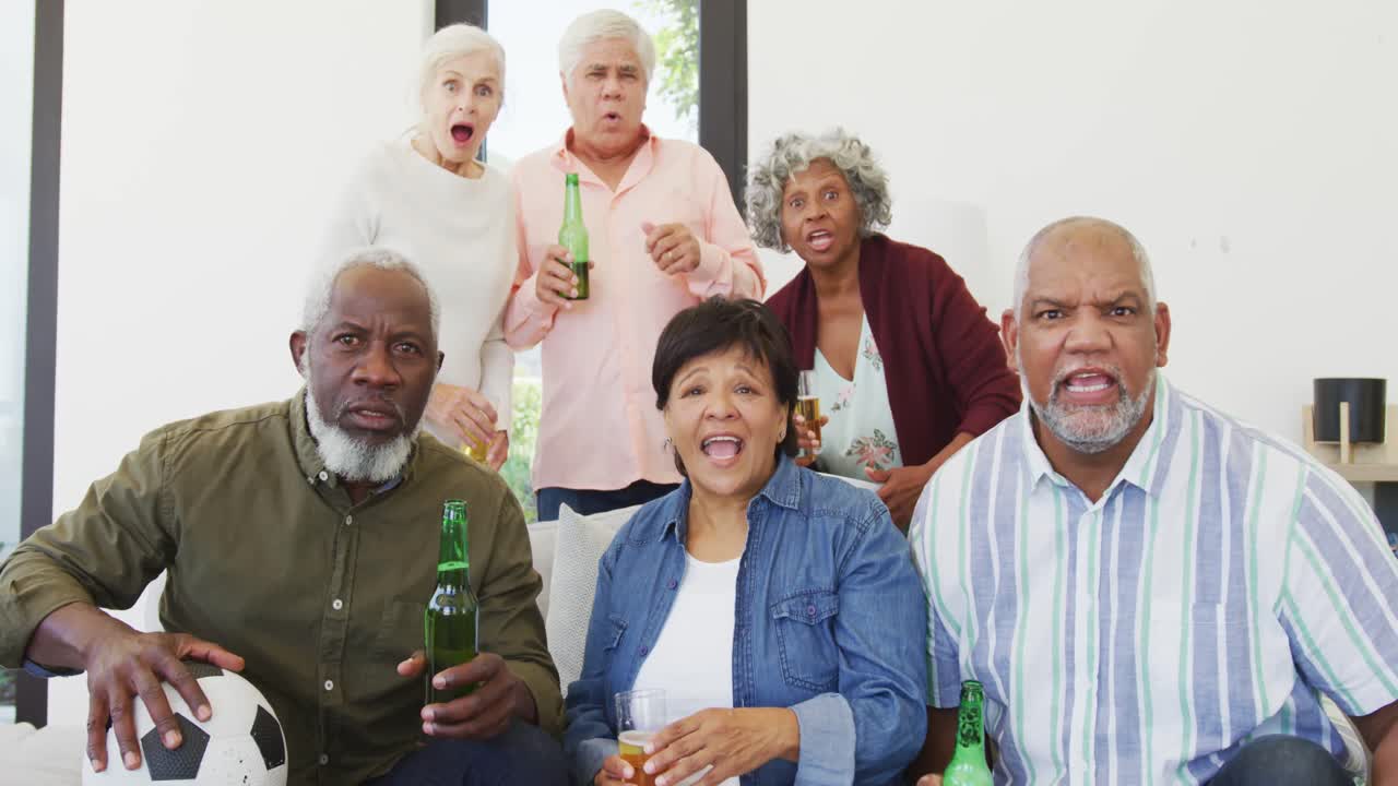 Retrato de idosos diversos felizes assistindo TV com cerveja em casa de repouso