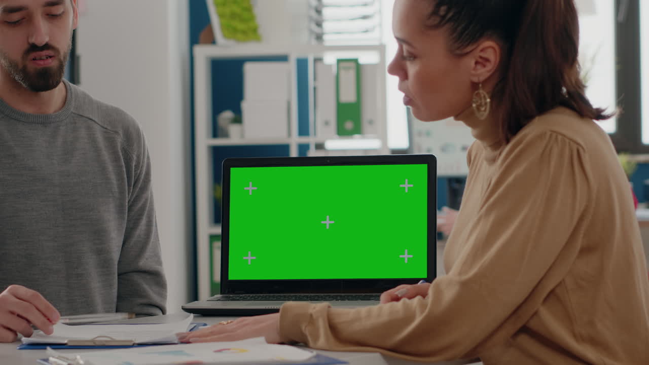 Close up of coworkers using laptop with green screen