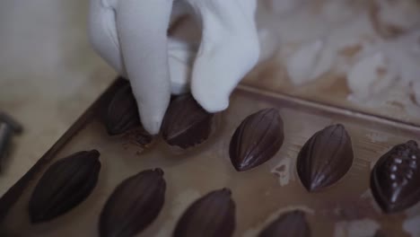 con el guante quitando a mano un pedazo de chocolate elaborado del moho