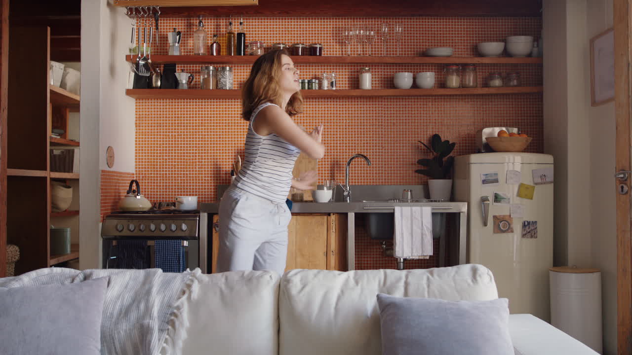 giovane donna felice che balla in cucina celebrando uno stile di vita di successo godendo di una allegra celebrazione della danza della vittoria a casa nel fine settimana