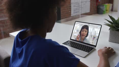 African-american-businesswoman-sitting-at-desk-using-laptop-having-video-call-with-female-colleague