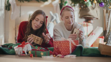 sisters making cardboard house ornaments during christmas at home