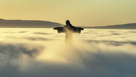 sonnenaufgang über den wolken, vögel kreuzen den horizont an der statue und der nebel bewegt sich