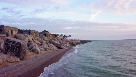 aerial view of abandoned seaside fortification buildings at karosta northern forts on the beach of baltic sea in liepaja, latvia, calm sea in the evening, low wide angle drone shot moving forward