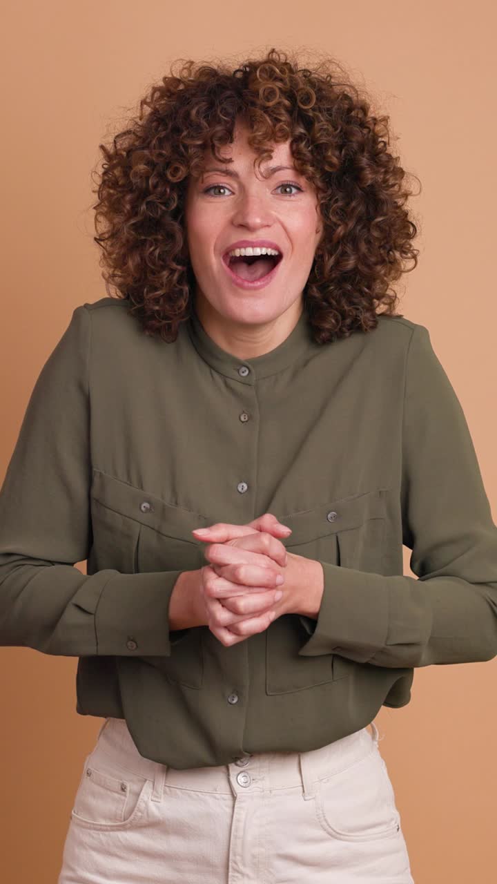 Stunned young woman standing with opened mouth on beige background. Vertical orientation