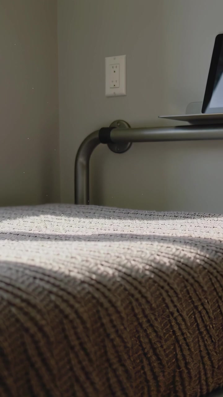 Vertical video: Tilting camera starting low revealing brown cushion at corner, outlet, rail, tablet