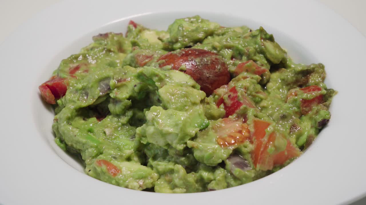 persona sumergiendo chips de tortilla en un tazón de guacamole, primer plano