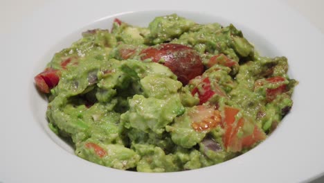 Person-dipping-tortilla-chip-in-bowl-of-guacamole,-Closeup