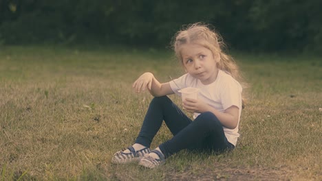 girl in white t-shirt and black pants eats tasty yogurt