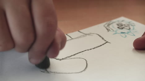 a child draws an animal with a black crayon as the camera tracks left