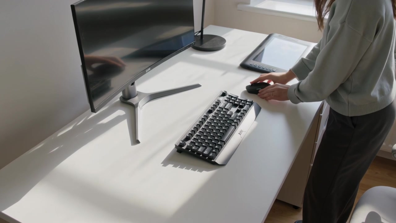 Kvinde i lys sweater nærmer sig, justerer tastatur og mus, forbereder skrivebord derhjemme, med kopirum.