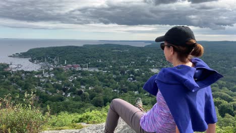 4k woman gazing down on camden maine from atop mount battie